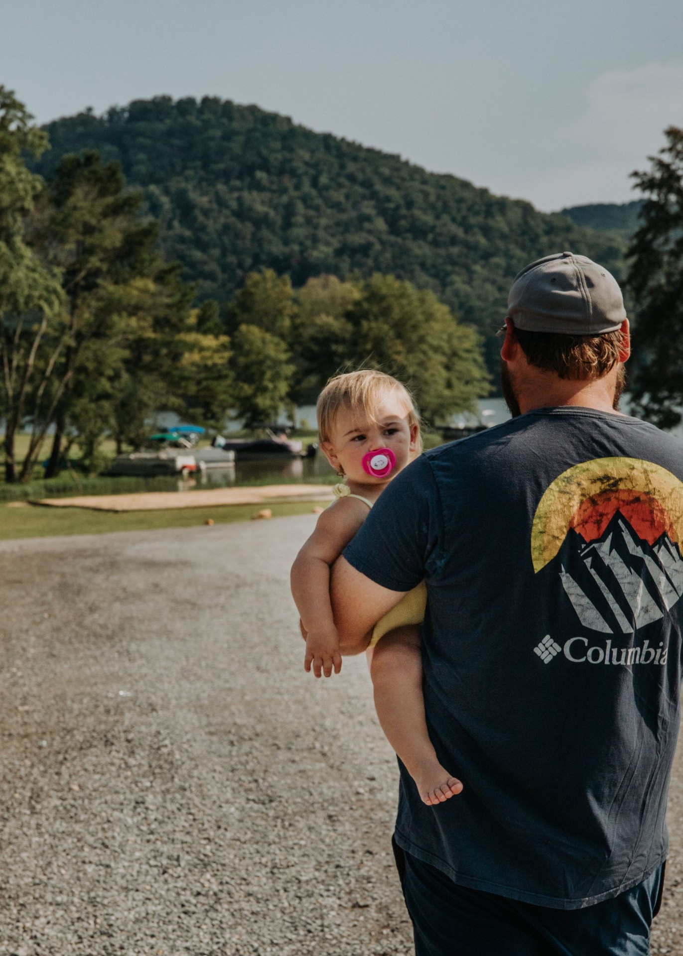 Parent carrying a child with the lake and hills behind them
