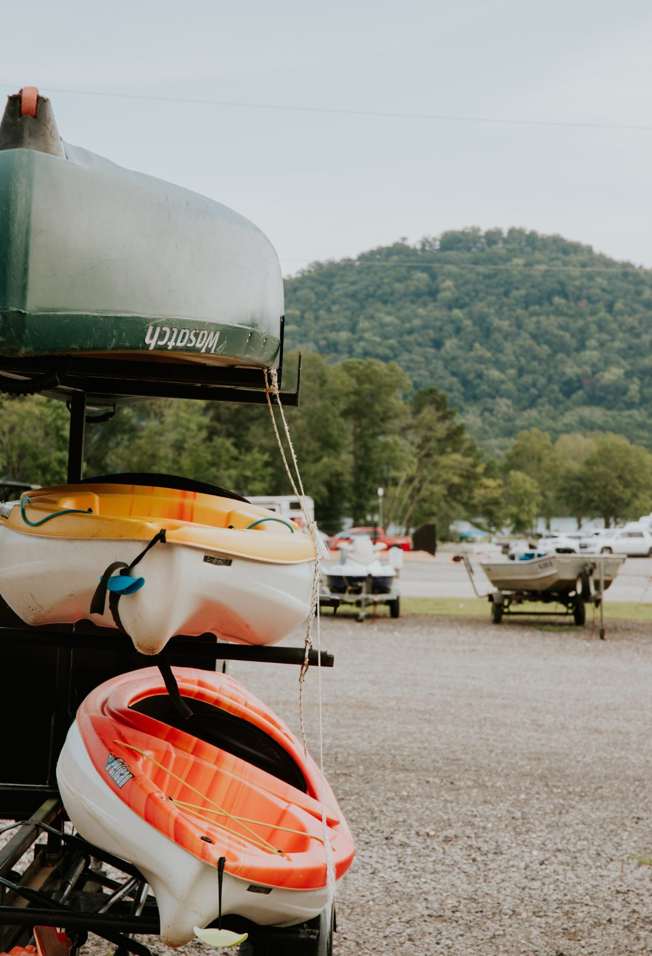Kayaks and canoes stacked with mountain views in the background