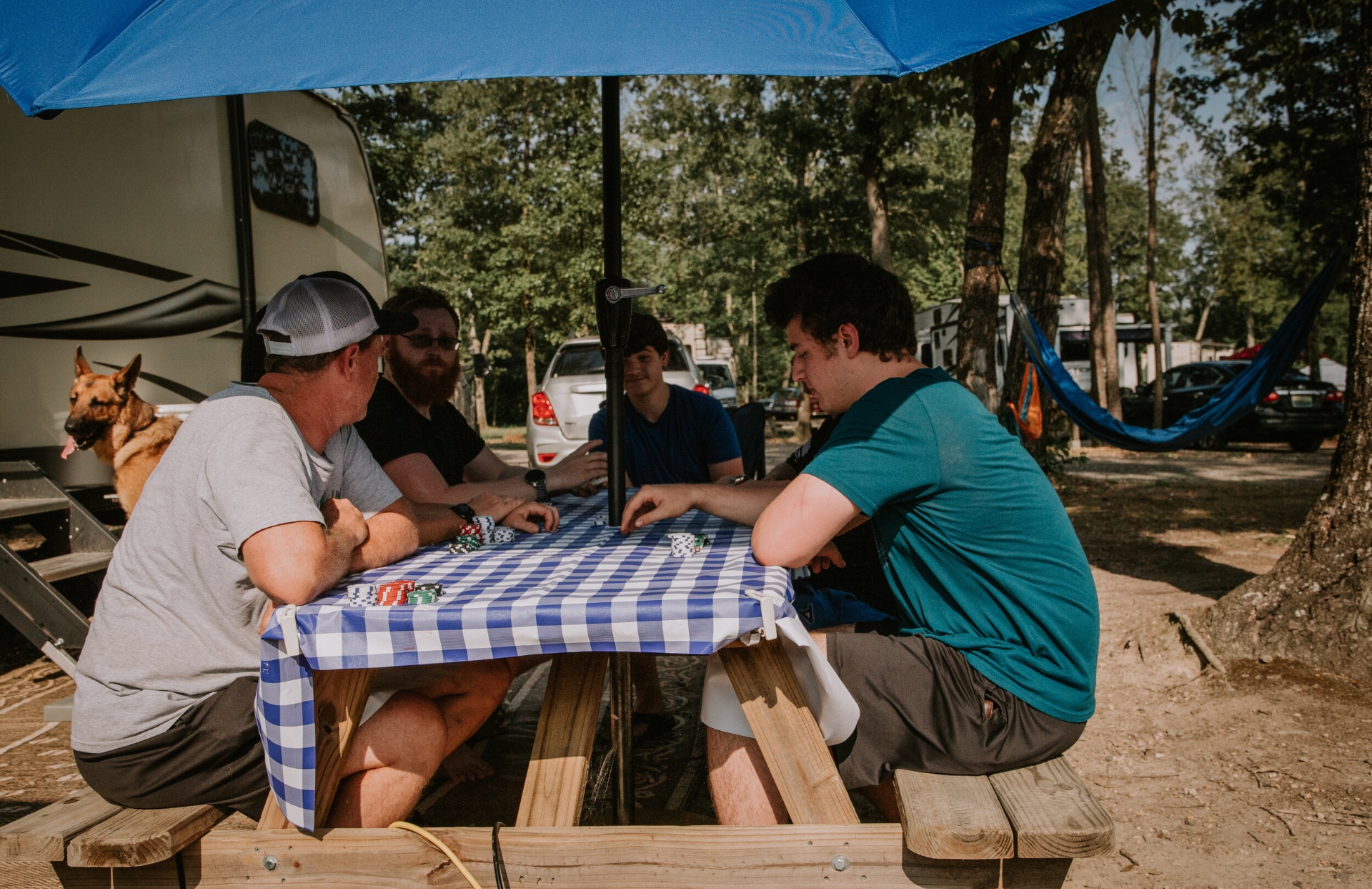 Guests gathered around a picnic table playing cards at their campsite