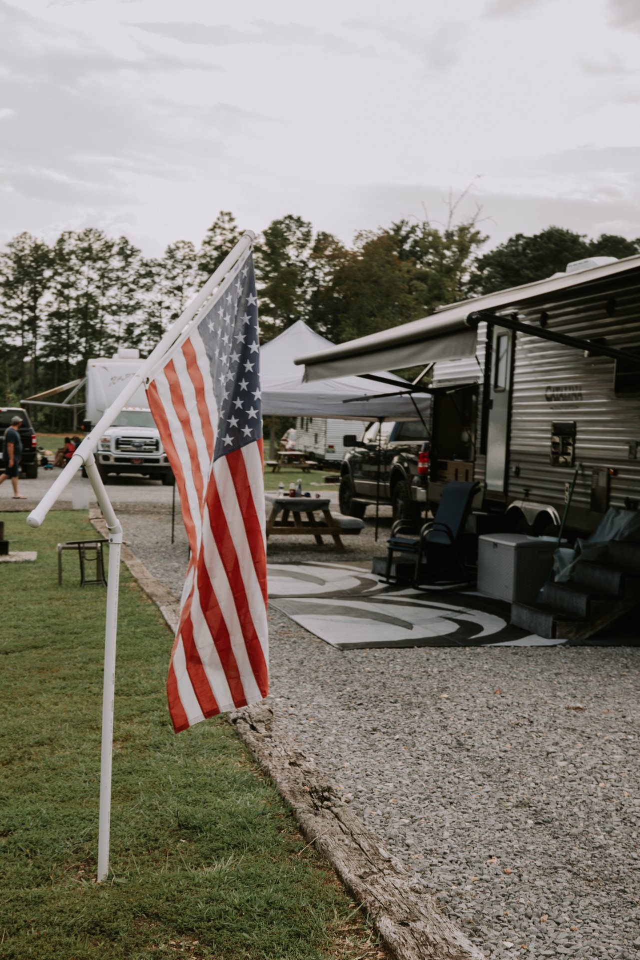 American flag flying at a campsite with RV and awning