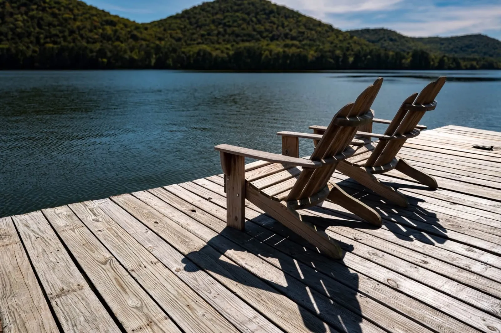 Two wooden Adirondack chairs on a dock overlooking Neely Henry Lake